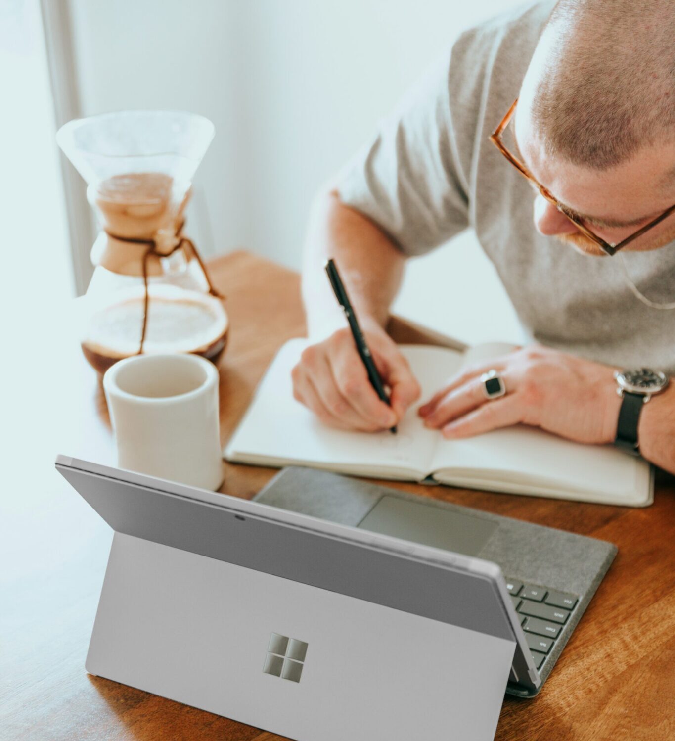 4-Ways-Small-Businesses-Can-Leverage-Microsoft-Copilot-for-SMBs-scaledjpg | ALCON DTS: Austin Best Managed IT Support Services a man sitting at a table writing on a notebook